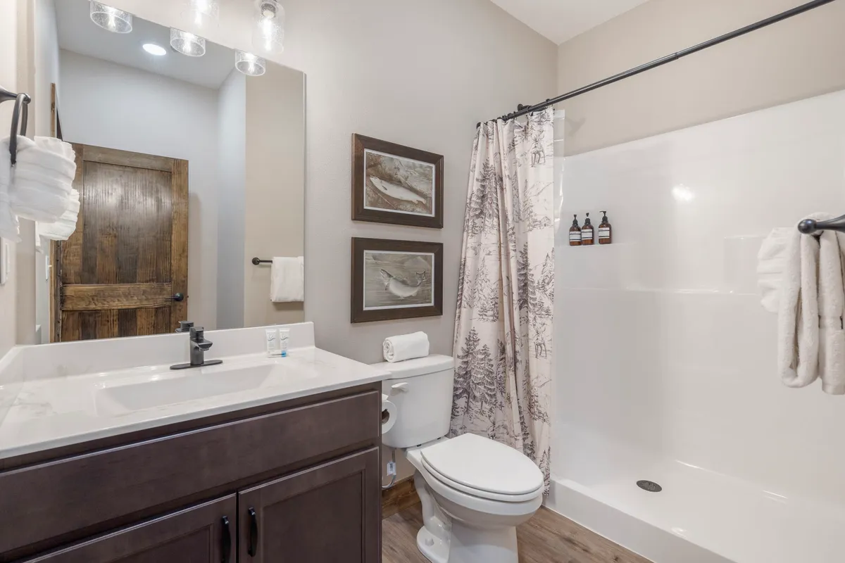 A serene bathroom with a modern sink, toilet, glass shower, and colorful wall art. The space feels fresh, clean, and private—ideal for unwinding and personal care at the end of an adventurous day.