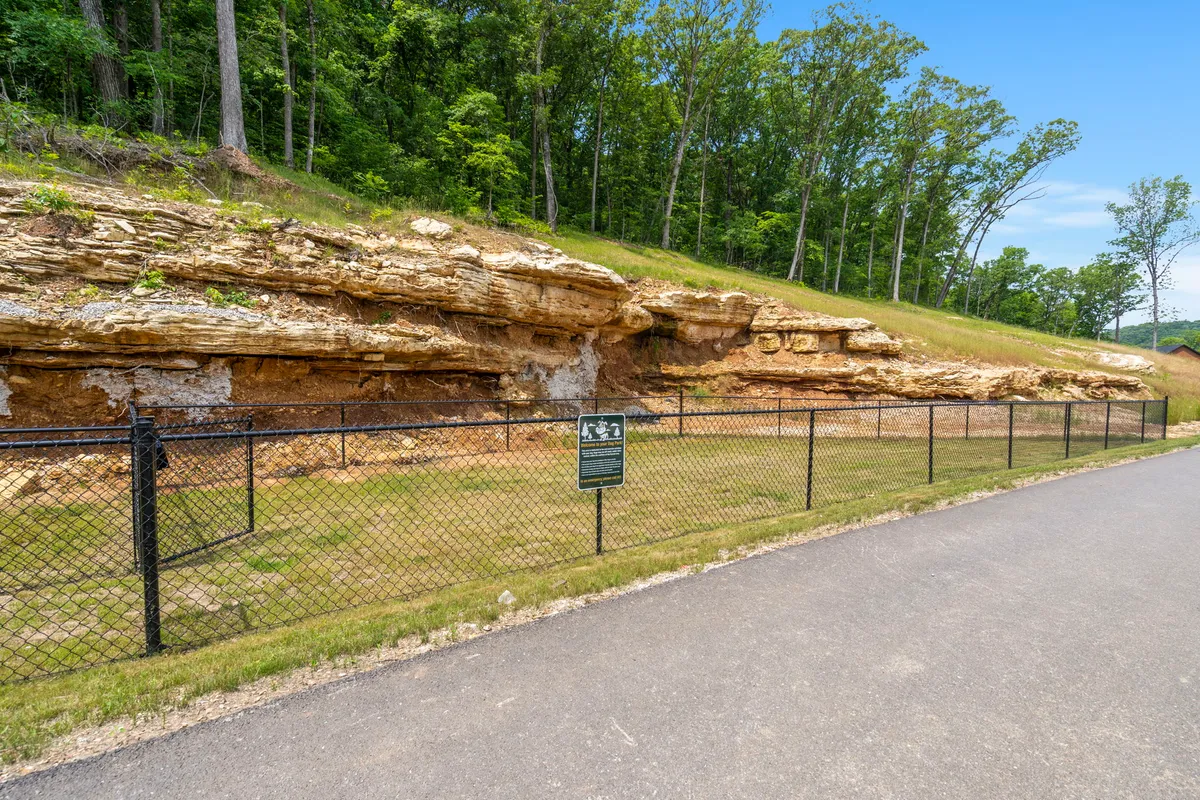 A scenic exterior showing a distinctive rock formation within a fenced area, surrounded by trees and open space, suggesting opportunities for hiking, nature walks, and exploration.