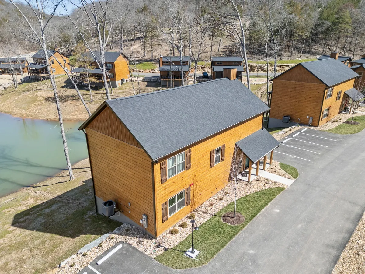 A tranquil lakeside setting with wooden cabins, a peaceful lake, and landscaped pathways. The scene offers opportunities for fishing, hiking, and relaxing by the water, all with a backdrop of sunset hues and natural beauty.