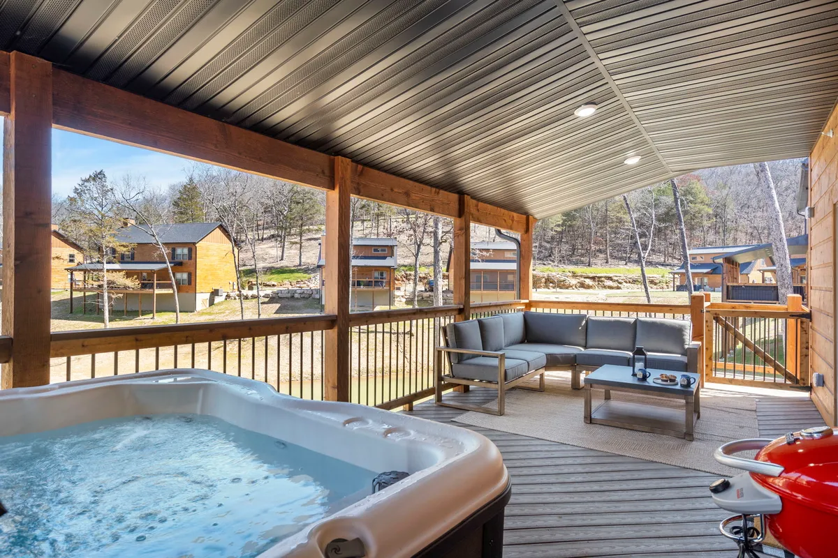 This image showcases a tranquil wooden deck featuring a private hot tub, ample outdoor seating, and a scenic view of the surrounding landscape. The wooden railing and lush greenery help blur the line between indoor comfort and outdoor relaxation, while the inviting mood is enhanced by soft lighting and open sky views.