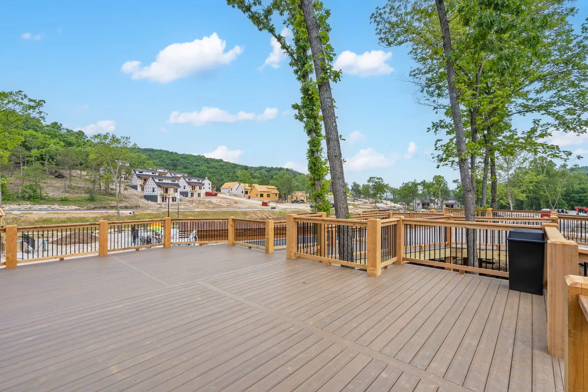 This image provides a wider view of the wooden deck, surrounded by trees and overlooking scenic hills. It depicts a space ideal for group gatherings, morning coffee with a view, or quiet moments stargazing in the evening.